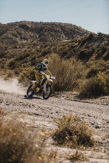 Männlicher Biker fährt Motorrad in der Wüste an einem sonnigen Tag - DMGF00549