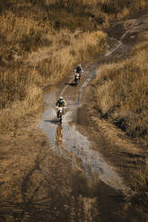 Männliche Motorradfahrer auf nasser Straße bei Enduro-Motorradrennen - DMGF00551