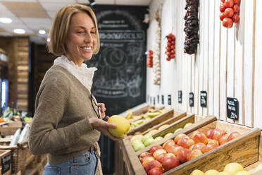Lächelnde Frau kauft Obst im Supermarkt - PNAF01914