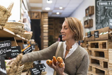 Blonde Frau sammelt Karotten im Supermarkt - PNAF01919