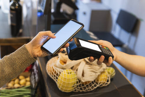 Female customer paying online through mobile phone at supermarket - PNAF01922