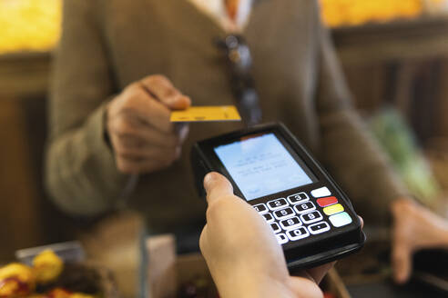 Frau bezahlt Rechnung mit Kreditkarte im Supermarkt - PNAF01923