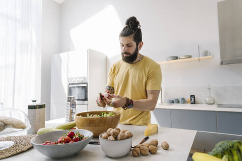 Man with beard cutting vegetable in kitchen - EYAF01640