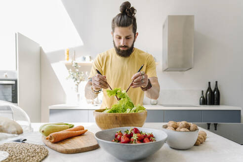 Man mixing vegetable while preparing salad at home - EYAF01643