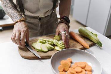 Mann schneidet Zucchini in der Küche zu Hause - EYAF01656