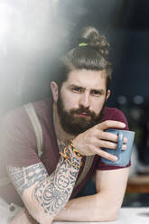 Mittlerer erwachsener Mann schaut weg, während er eine Kaffeetasse zu Hause hält - EYAF01663