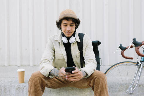 Man wearing knit hat text messaging through mobile phone - AGGF00113