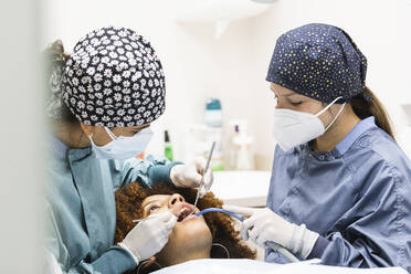 Female patient receiving treatment from dentists at clinic - PNAF01936