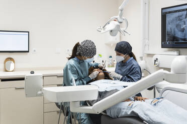 Female dentists giving dental treatment to patient at clinic - PNAF01955