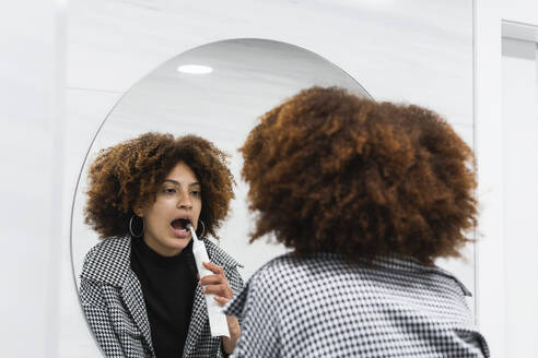 Afro-Patientin beim Zähneputzen vor dem Spiegel im Badezimmer einer Klinik - PNAF01958