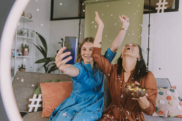 Glückliche Frauen, die mit Konfetti feiern, während sie zu Hause filmen - MFF08067