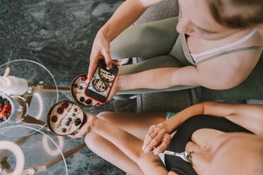 Frauen fotografieren Joghurt-Obstschalen mit dem Smartphone - MFF08107