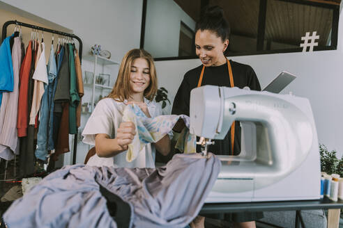 Lächelnde Modedesigner beim Betrachten von Stoffen im Workshop - MFF08165