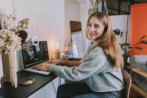 Weibliche Influencerin, die zu Hause über ihren Laptop vloggt - MFF08199