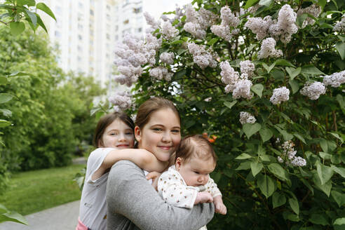 Mädchen umarmt Schwester mit Baby im Park - EYAF01673