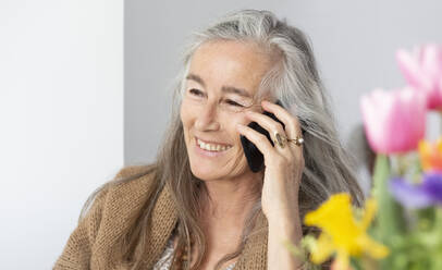 Smiling woman talking on mobile phone at home - FCF01982