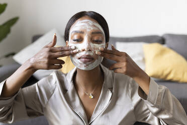 Young woman applying facial mask - JPTF00828
