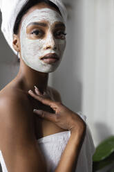 Woman with facial mask wrapped in towel at home - JPTF00836