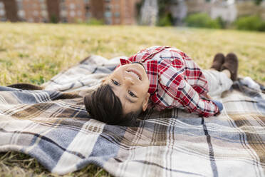 Junge lächelnd auf Picknickdecke liegend - JCCMF02858