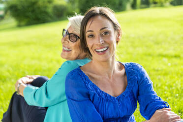 Happy mid-adult woman with senior woman sitting in public park - OIPF00882