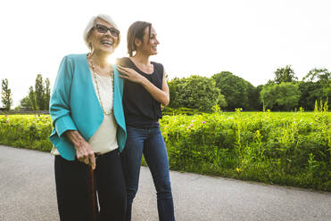 Glückliche ältere Frau, die mit einer mittelalten Frau im Park spazieren geht - OIPF00903
