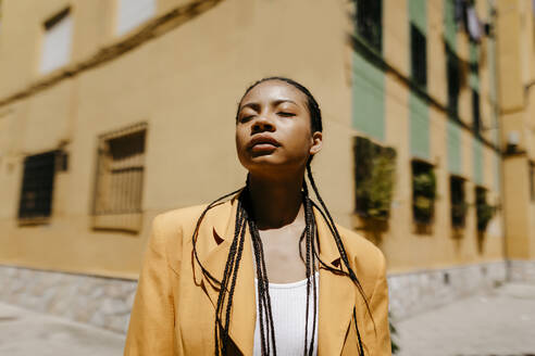 Woman with braided hair standing during sunny day in city - TCEF01924