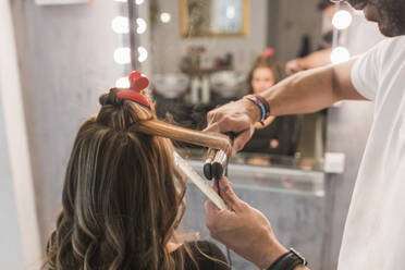 Männliche Fachkraft stylt die Haare einer Kundin im Friseursalon - JRVF01004
