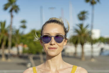 Smiling woman wearing sunglasses on sunny day - AFVF08859