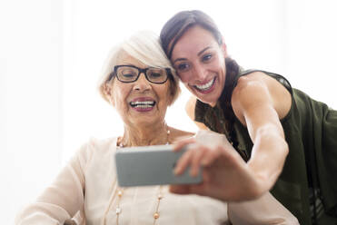 Glückliche Frau nimmt Selfie mit Großmutter durch Handy zu Hause - OIPF00929