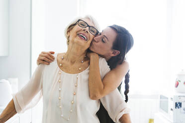Mid erwachsene Frau mit Arm um küssen Großmutter Wange zu Hause - OIPF00941