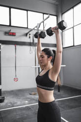 Active woman exercising with dumbbells in gym - SNF01481