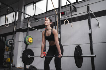Aktive Frau hebt Gewicht im Fitnessstudio - SNF01490