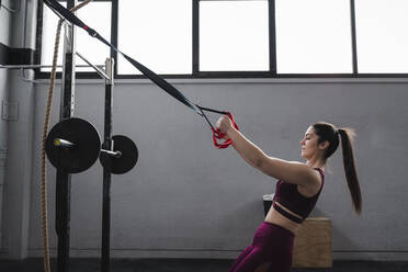 Sportswoman exercising with resistance band in gym - SNF01494