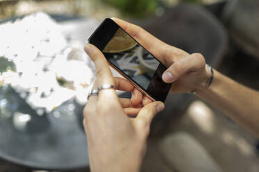 Mittlere erwachsene Frau, die ein Smartphone benutzt, während sie im Restaurant sitzt - VGF00402