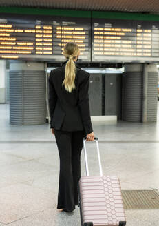 Female flight attendant walking with suitcase at airport - JCCMF02882