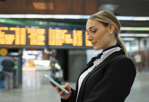 Young air stewardess using smart phone at airport - JCCMF02885