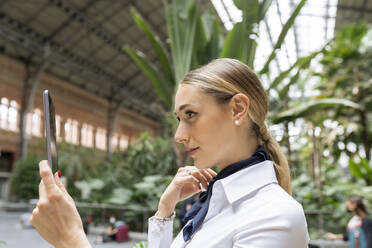 Selbstbewusste weibliche Flugbegleiterin macht ein Selfie auf einem digitalen Tablet im Garten - JCCMF02887