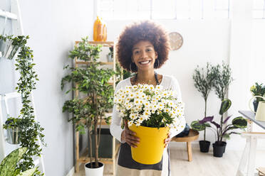 Lächelnde Blumenhändlerin mit Blumenstrauß in einem Geschäft - GIOF12915