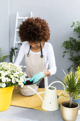 Female florist smiling while gardening at plant shop - GIOF12958