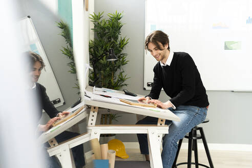 Männlicher Design-Profi, der am Schreibtisch sitzend ein digitales Tablet benutzt - GIOF12990