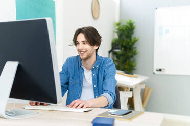 Männlicher Unternehmer, der einen Computer bei der Arbeit im Büro benutzt - GIOF13000