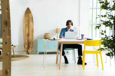 Männlicher Unternehmer mit Laptop bei der Arbeit im Büro - GIOF13007