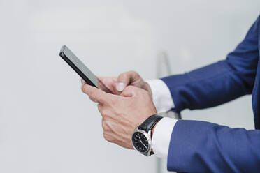 Businessman using mobile phone while leaning on railing - EBBF03993