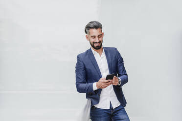 Male entrepreneur using smart phone while leaning on railing - EBBF03995