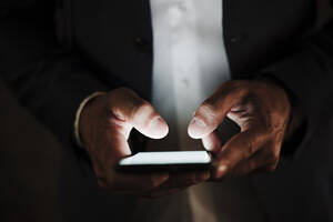 Männlicher Unternehmer benutzt Smartphone im Dunkeln - EBBF04014