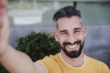 Lächelnder Mann nimmt Selfie durch Smartphone - EBBF04018