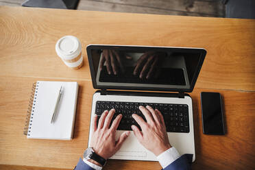 Geschäftsmann arbeitet am Laptop in der Cafeteria - EBBF04037