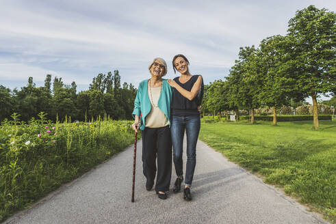 Lächelnde Großmutter und Enkelin gehen zusammen auf der Straße im Park - OIPF00951