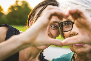 Enkelin und Großmutter machen Herz mit Hand im Park - OIPF01000