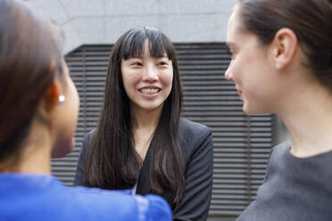 Smiling female entrepreneur having discussion with colleagues - IFRF00861